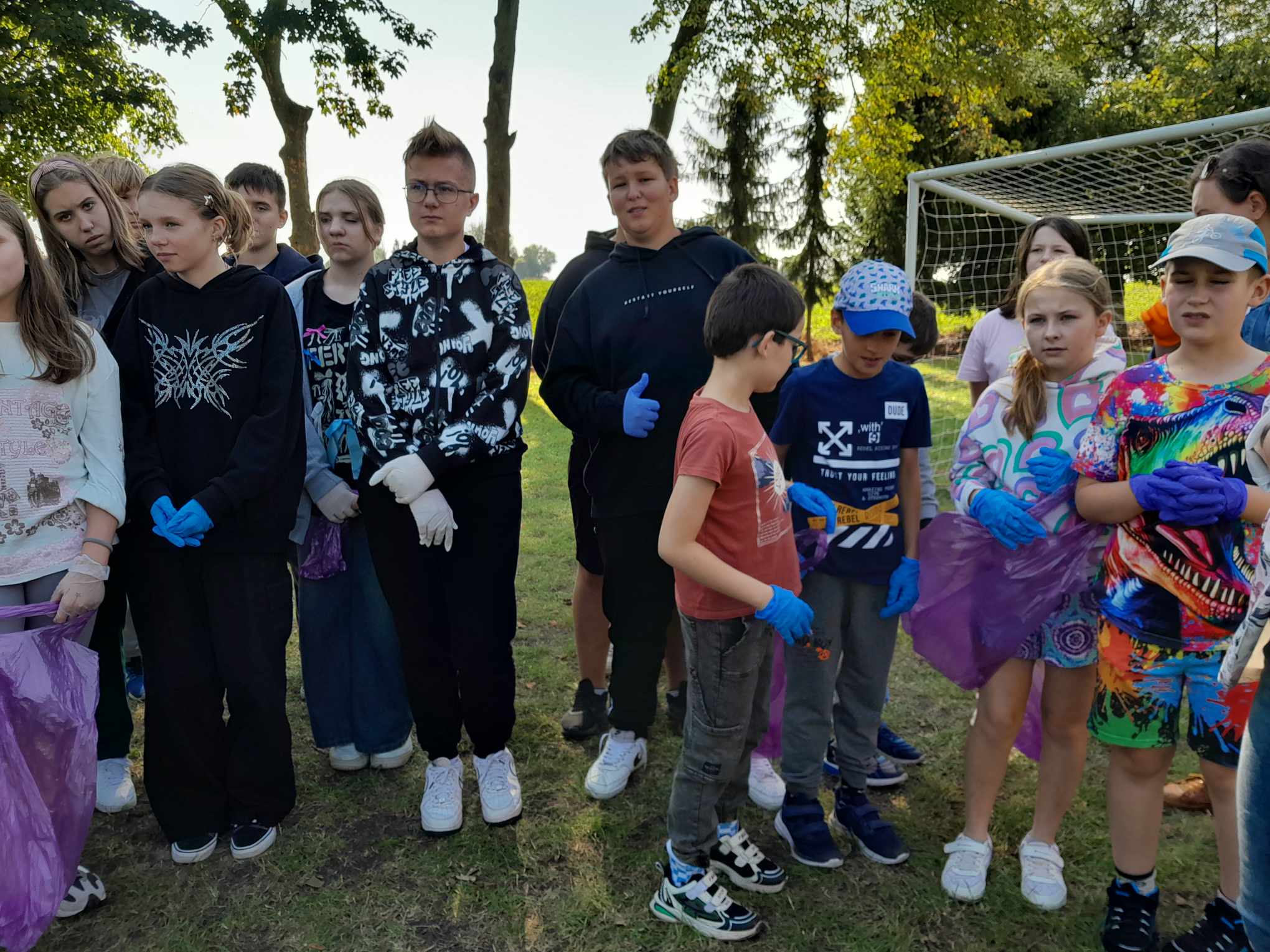 Uczniowie szkoły z workami na śmieci na boisku szkolnym 