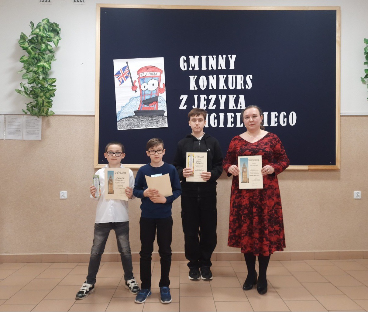 Nauczycielka i trzech chłopców na tle tablicy dekoracyjnej