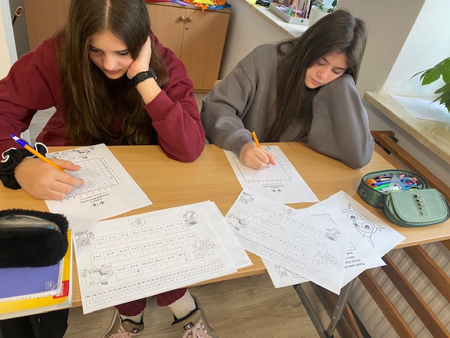 Dwie uczennice rozwiązują przy stoliku łamigłówkę matematyczną