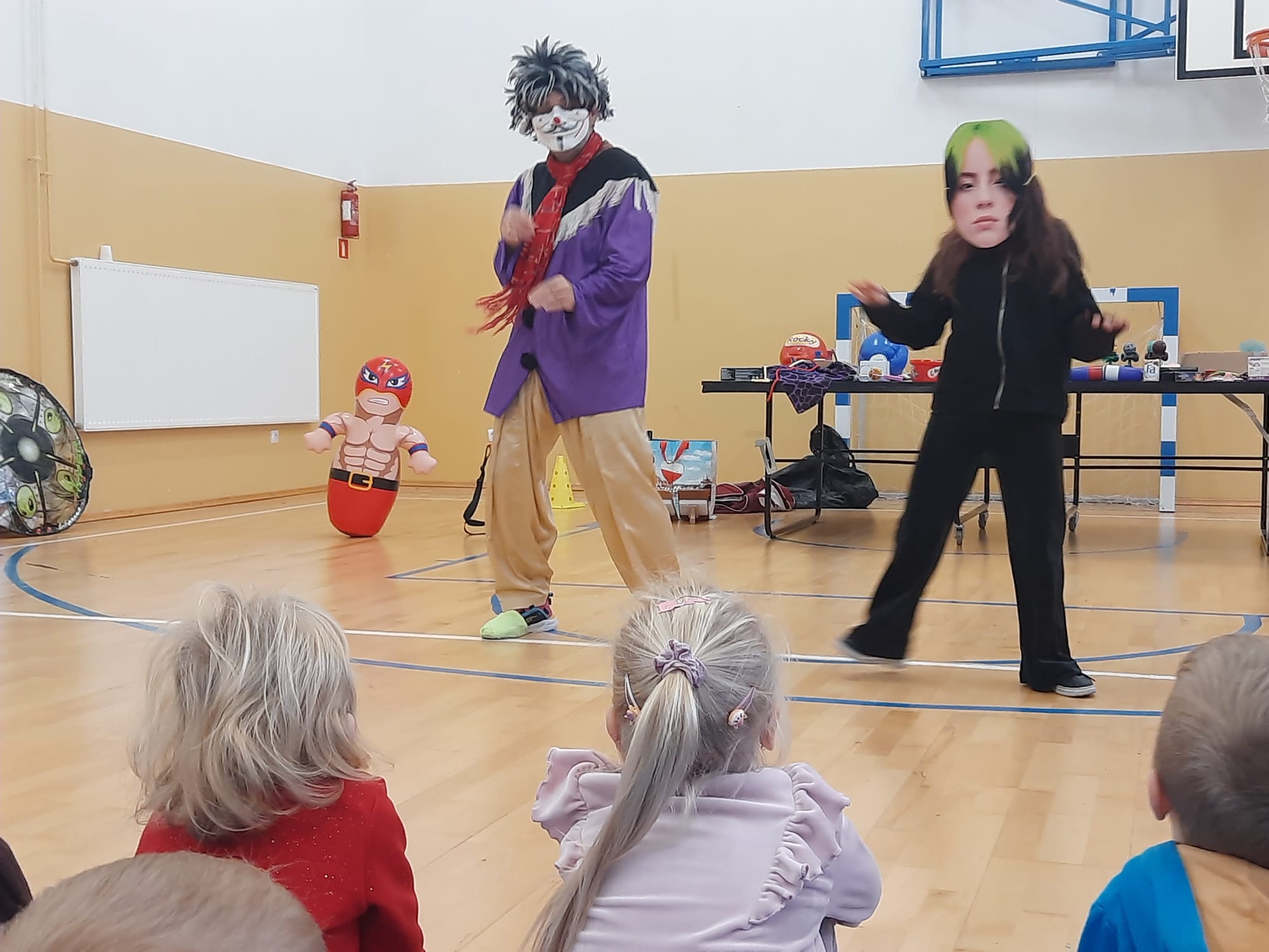 Klaun tańczy z uczennicą w masce przed widownią