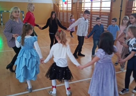 Uczniowie tańczą w kółeczku z nauczycielami