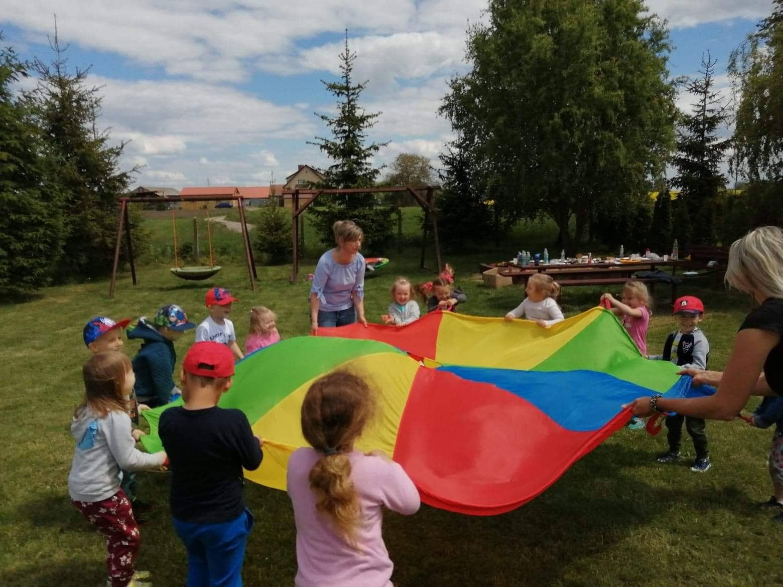 Nauczycielka i dzieci bawią się dużą kolorową chustą
