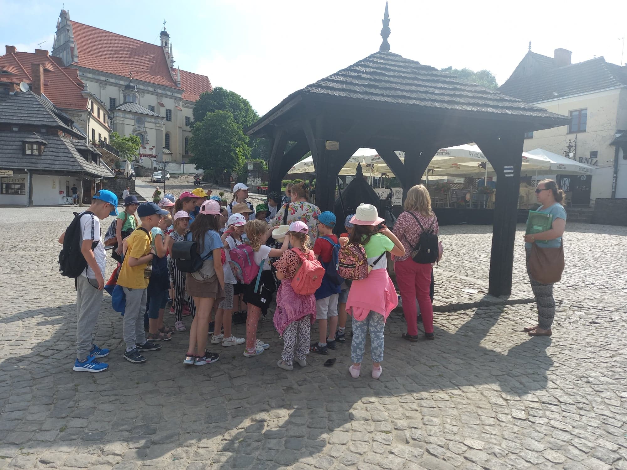 Uczniowie z opiekunkami przy zabytkowej studni na rynku w Kazimierzu Dolnym