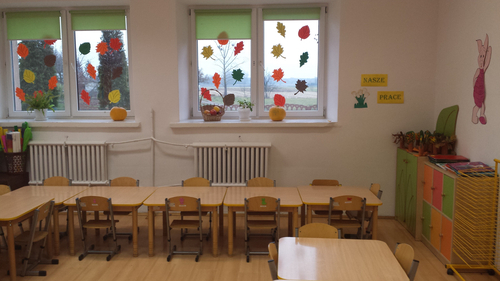 Pomieszczenie przedszkolne wyposażone w ławki, stoliki, szafki