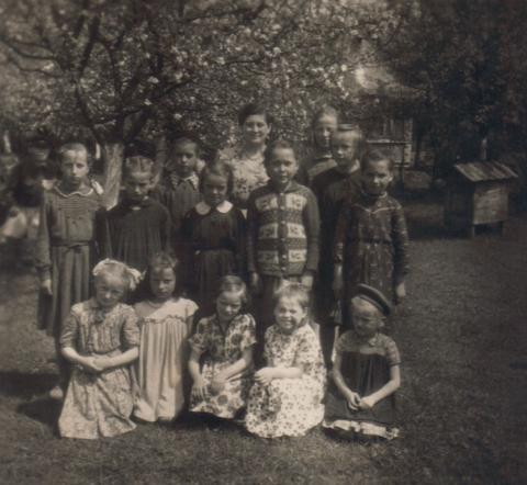 Stare zdjęcie, czarno-białe, grupa dzieci w różnym wieku, w tle sad jabłoni
