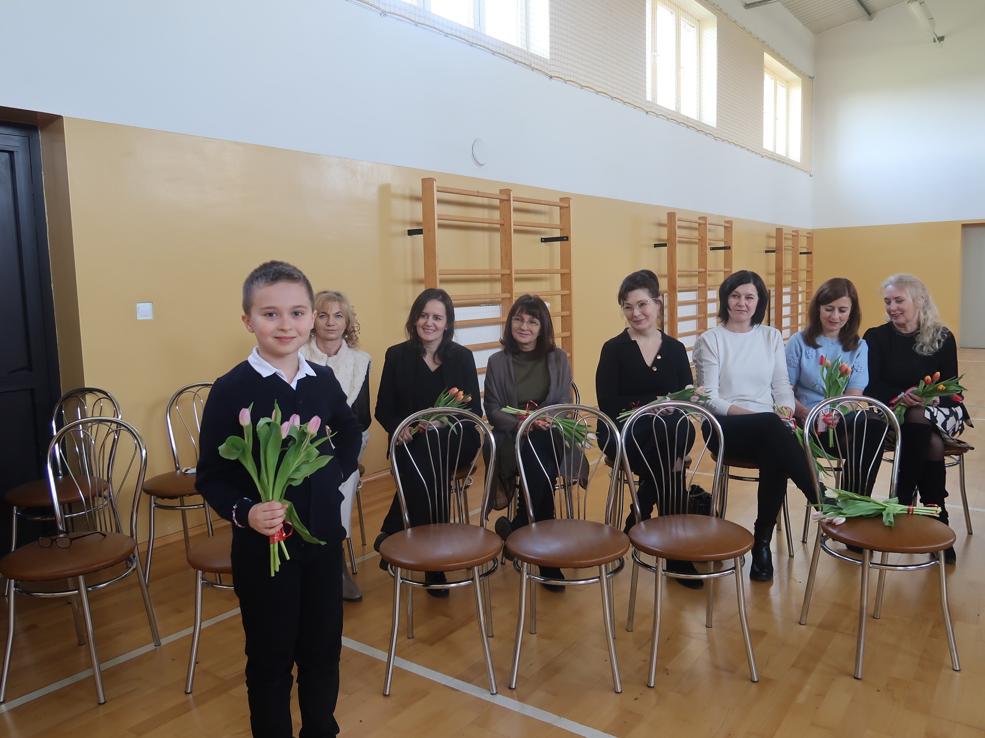 Uczeń trzymający kwiaty przed wręczeniem z okazji święta Kobiet
