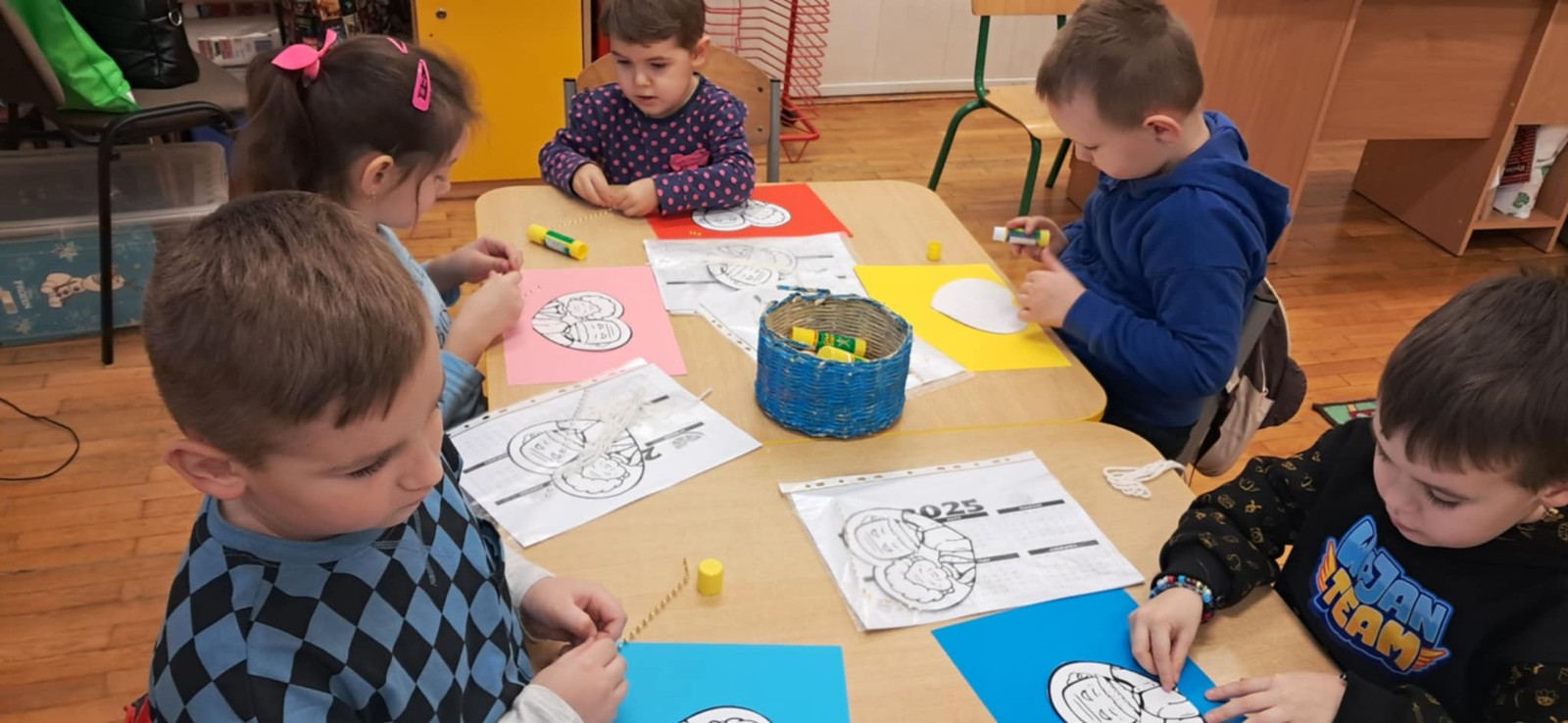 Dzieci wykonują kalendarze na Dzień Babci i Dziadka pod nadzorem Pani z Biblioteki i nauczycielek.