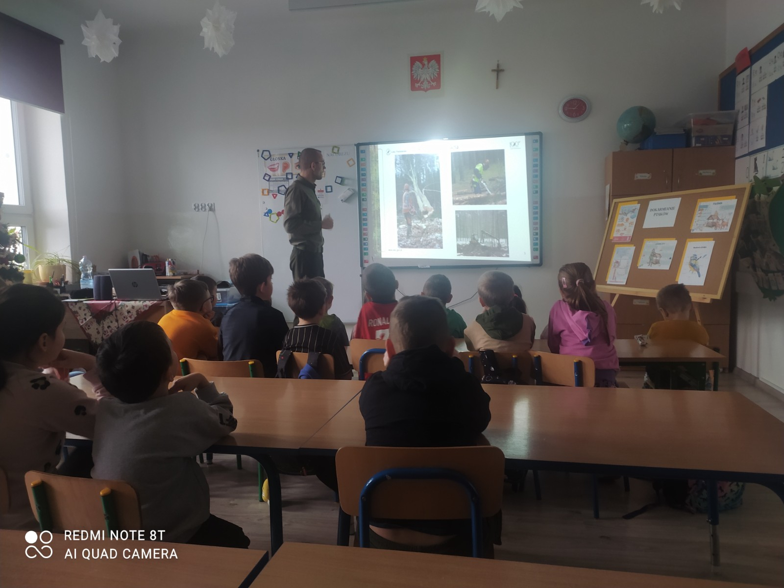 Dzieci i uczniowie oglądają prezentację przygotowaną przez leśnika.