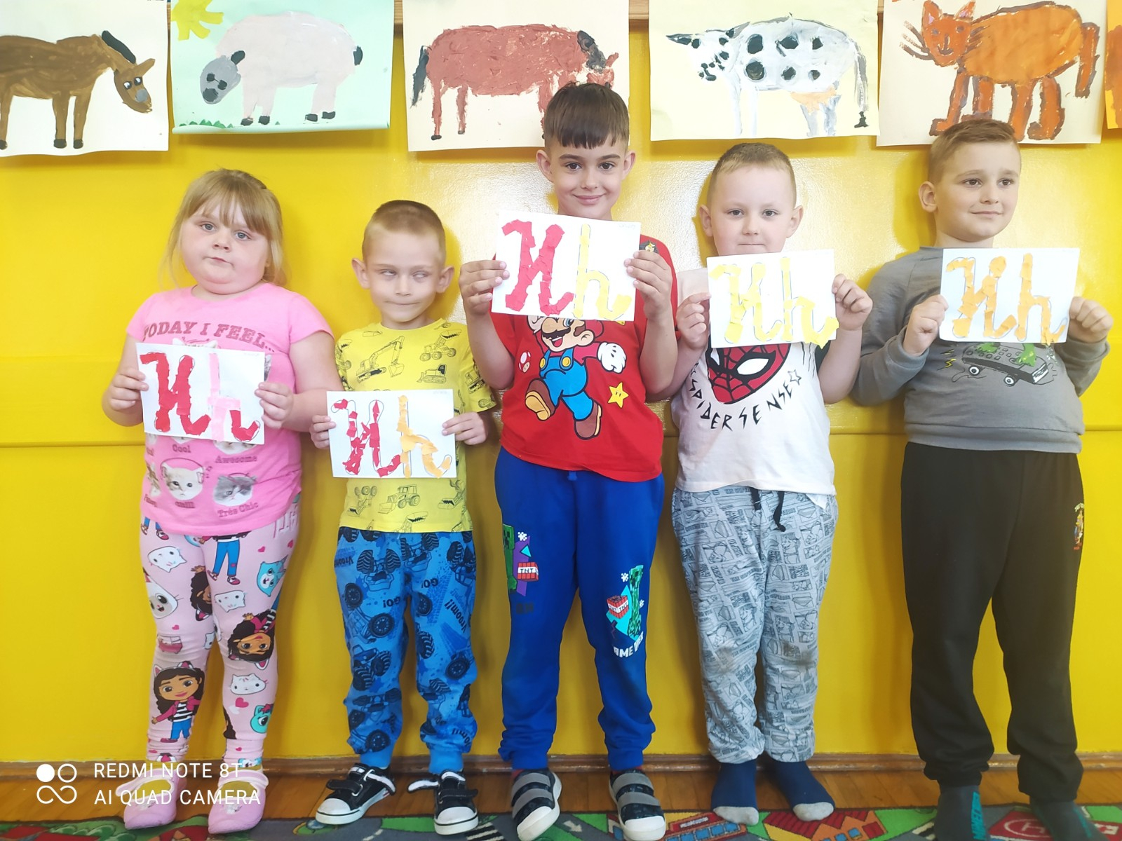 Dzieci prezentują się z wyklejanymi literkami.