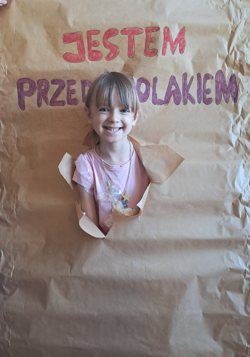 Przedszkolak prezentuje się do zdjęcia z napisem 