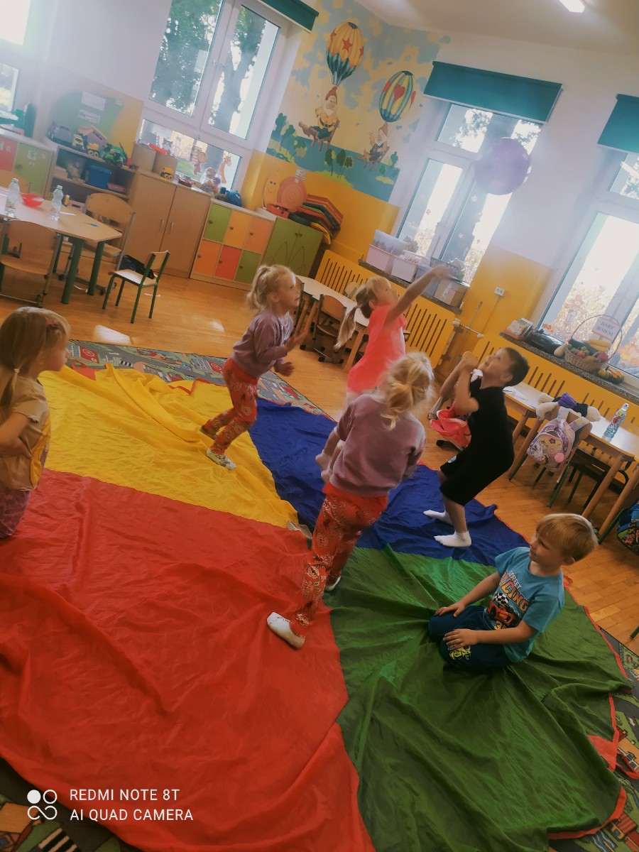 Dzieci biorą udział w zabawie z balonem.