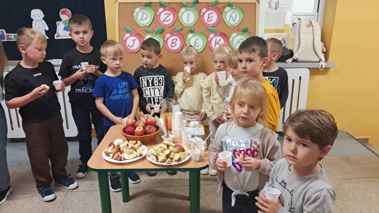 Dzieci pozują do zdjęcia przy stole zastawionym jabłkowymi smakołykami.