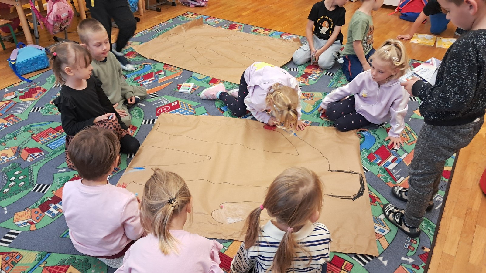 Dzieci odrysowują postać chłopca, a potem kolorują.