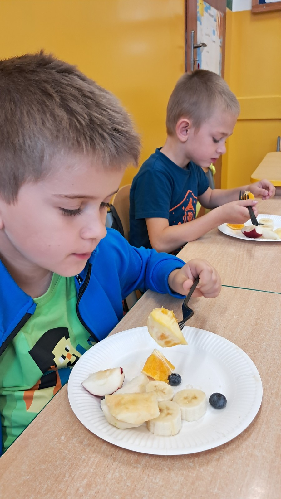 Dzieci jedzą owoce.