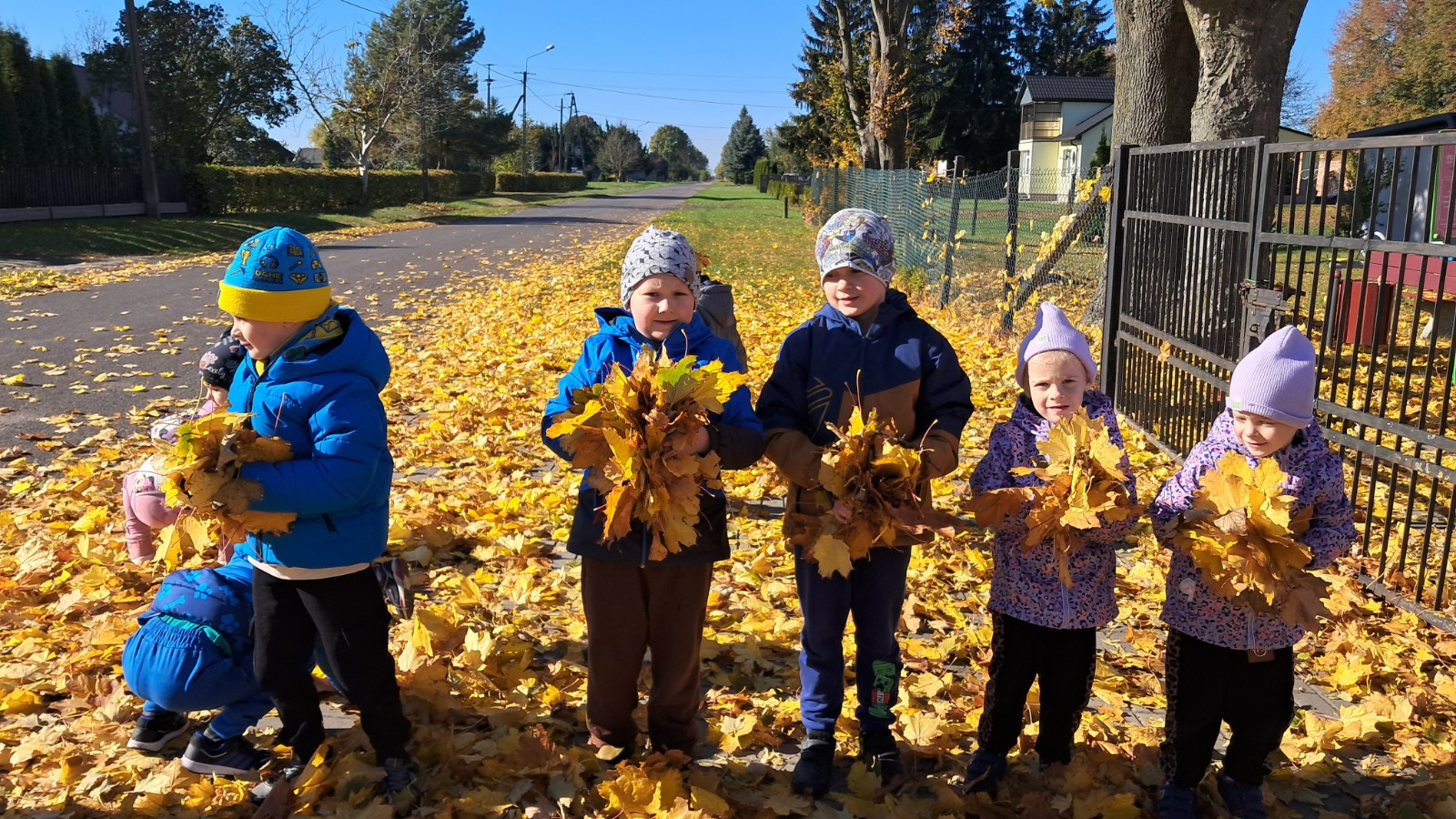 Dzieci prezentują się w tle jesiennych liści.