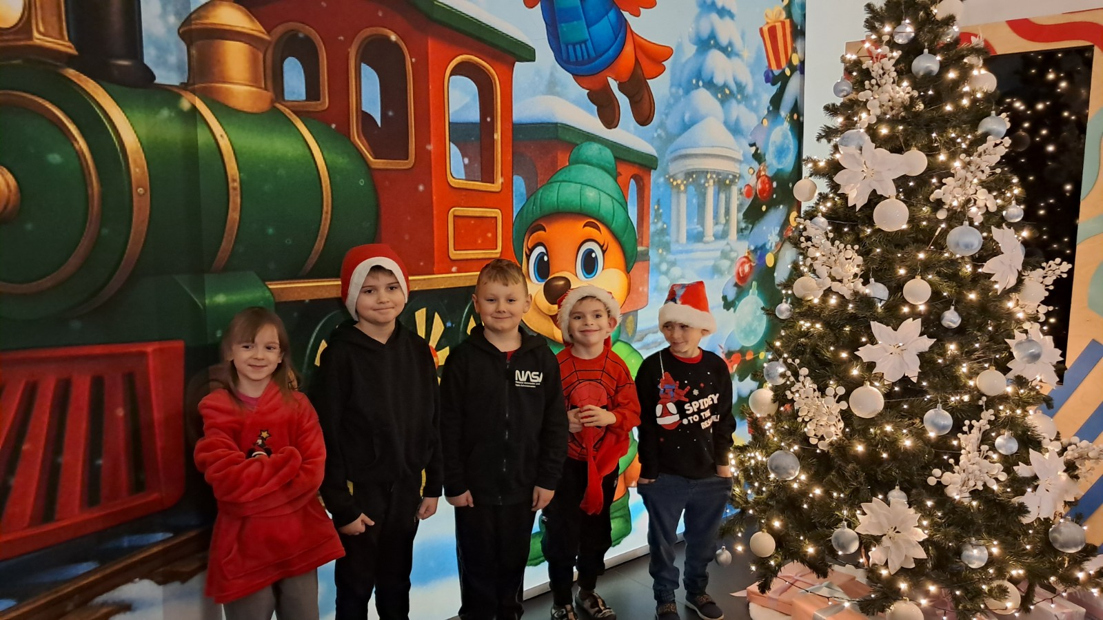 Dzieci pozują do zdjęcia w świątecznej scenerii.