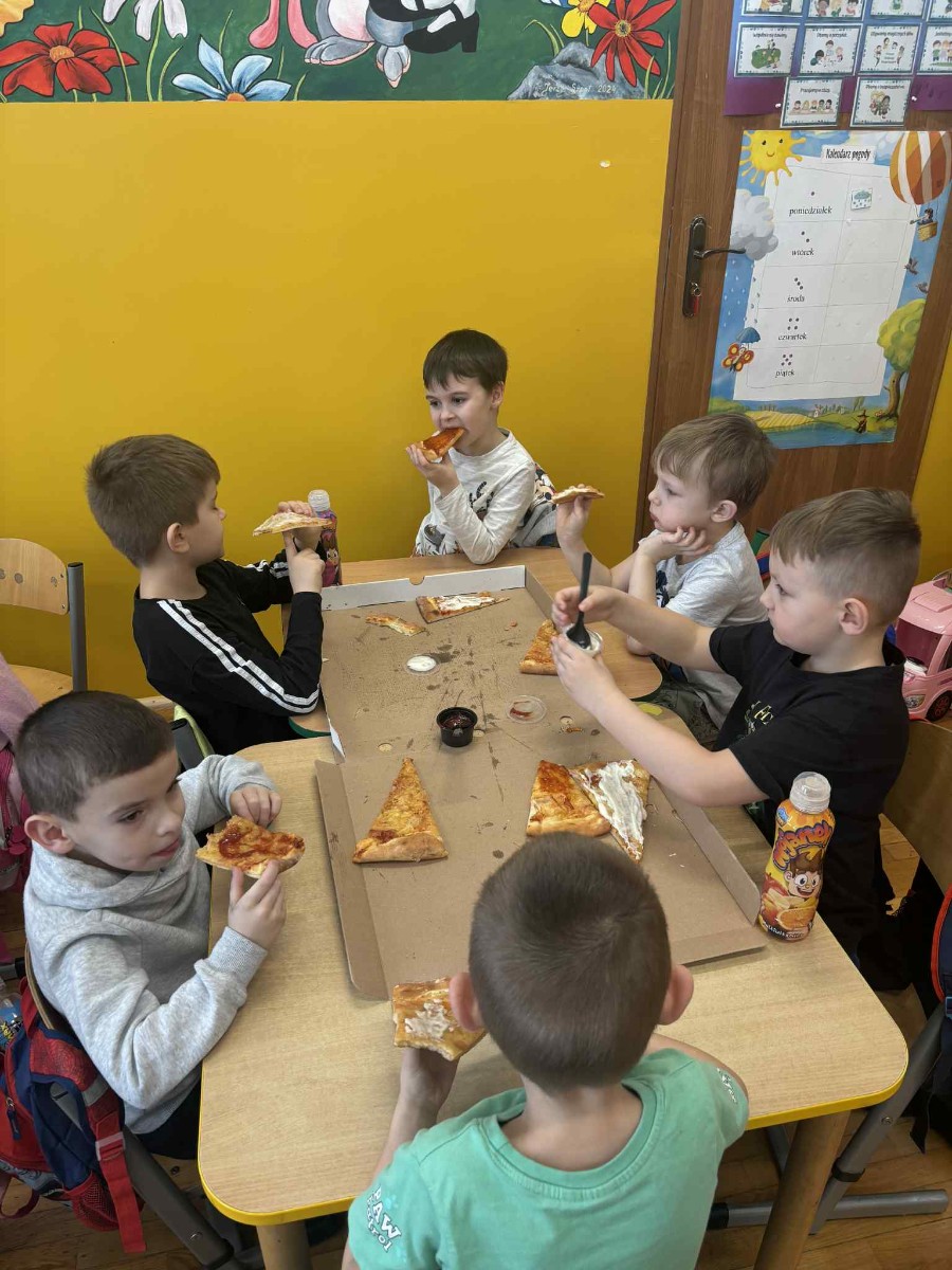 Dzieci degustują pizzę.
