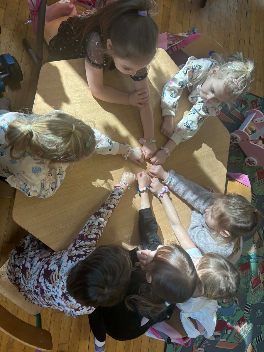 Dziewczynki pokazują swoje wyroby biżuteryjne.