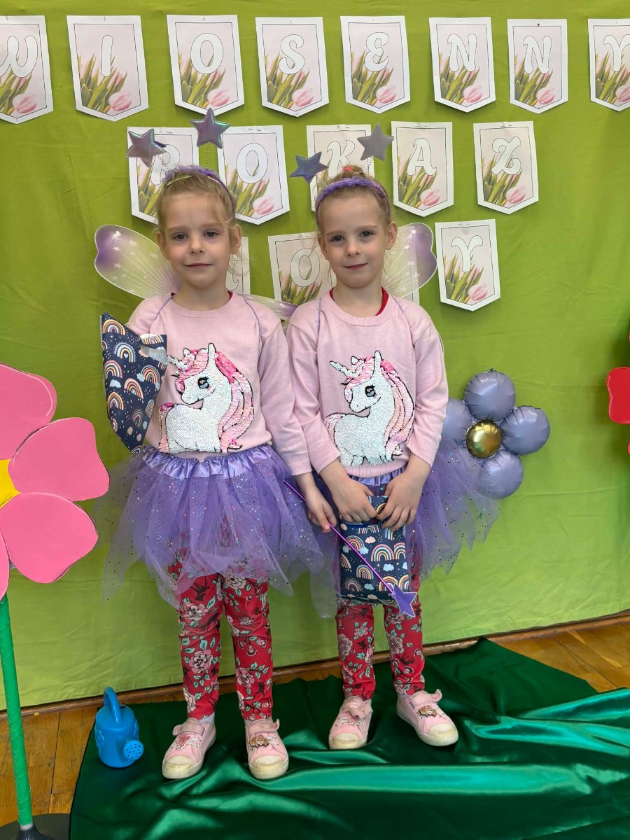 Dzieci prezentują się w wiosennych strojach.