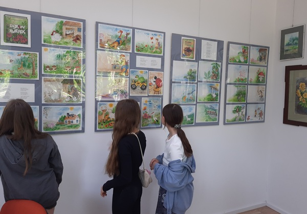 Grafika ilustrująca uczennice oglądające wystawę prac 