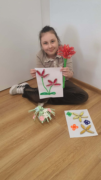 Grafika ilustrująca dziewczynkę trzymającą pracę plastyczną