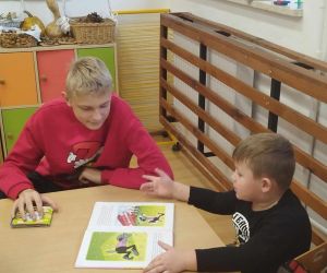 Zabawy integracyjne dla najmłodszych – uczeń klasy szóstej czyta przedszkolakowi