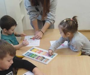 Zabawy integracyjne dla najmłodszych – przedszkolaki rysują z uczennicą klasy ósmej