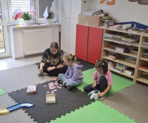 Zabawy integracyjne dla najmłodszych – uczennica klasy siódmej układa puzzle z przedszkolakami z grupy sześciolatków