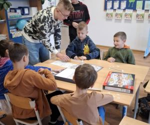 Zabawy integracyjne dla najmłodszych – uczniowie klasy ósmej i szóstej grają w grę planszową z uczniami klasy drugiej