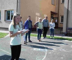 Uczennica klasy VIII odczytuje informacje dla pozostałych uczniów. W tle nauczyciele wychowawcy