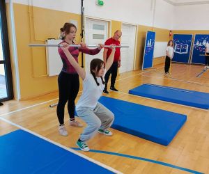 Uczennica podnosi sztangę pod okiem trenerki