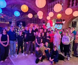 Grupa uczniów stoi na tle dekoracji z Mikołajem