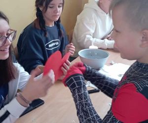 Uczennica trzyma uczniowi wróżbę zapisaną na czerwonym papierowym sercu