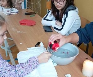 Uczennica przelewa wosk do miski z wodą