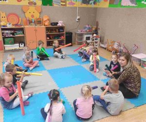 Przedszkolaki siedzą w kręgu z wychowawczynią