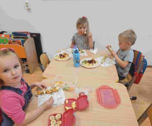 Chłopiec i dwie dziewczynki przy stole podczas poczęstunku