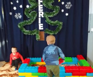 dzieci bawiące się dużymi klockami wewnątrz budynku.