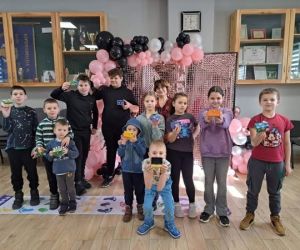 Grupa dzieci pozująca do zdjęcia wraz z wykonanymi przez siebie pracami plastycznymi.