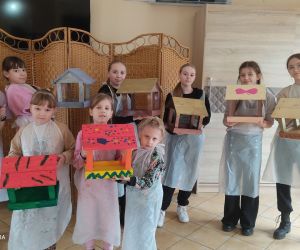 Dzieci pozujące z wykonanymi przez siebie karmnikami dla ptaków.