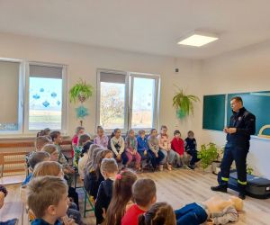Przedstawiciel straży pożarnej przemawia do młodszych uczniów