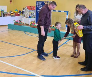 Pan inspektor oświaty i pani dyrektor wręczają dyplom i nagrodę jednemu z laureatów