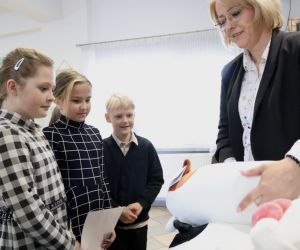 Zdjęcie przedstawia troje dzieci i osobę dorosłą wręczającą im nagrody.