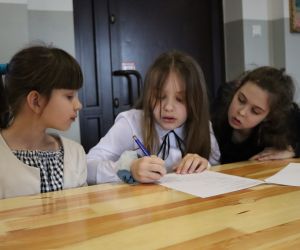 Na zdjęciu widoczne są dzieci rozwiązujące zadania testowe.