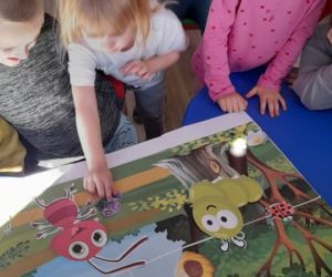 Na zdjęciu widoczne są małe dzieci oglądające ilustracje.