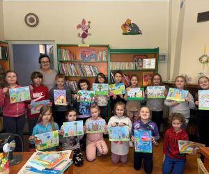 Na zdjęciu widoczna jest grupa dzieci prezentująca swoje rysunki.