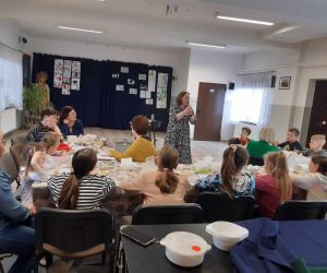 Na zdjęciu widoczne są dzieci i dorośli podczas warsztatów wielkanocnych.