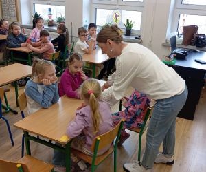 Prowadząca rozdaje materiały na kartki