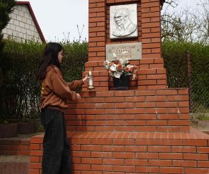 Uczennica składa znicz pod pomnikiem w miejscowości Staszic