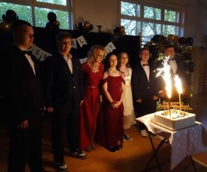 Uczniowie z wychowawcą stoją przed tortem