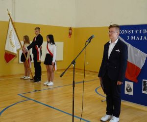 Poczet sztandarowy i uczeń prowadzący uroczystość podczas śpiewania hymnu państwowego